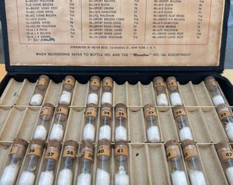 Box of 27 antique glass watch vials, each containing watch crowns.