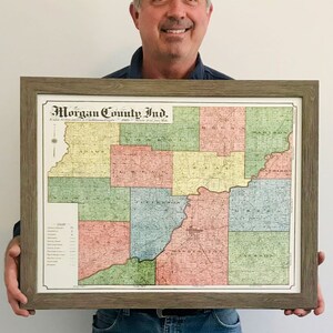 May include: A framed vintage map of Morgan County, Indiana, with a color-coded key showing the townships. The map is framed in a light brown wood frame with a white mat.