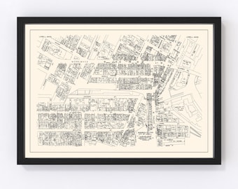 May include: A black and white map of Lowell, Massachusetts, showing the city's streets and blocks. The map is framed in a black frame and is hanging on a white wall.