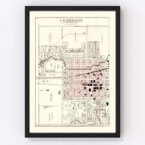 May include: A vintage map of LaGrange, Georgia, printed in black and white with red highlights. The map shows the city's streets, blocks, and landmarks. The map is framed in a black frame.