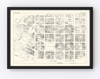 May include: A black and white map of downtown St. Paul, Minnesota, showing the city's street grid and block numbers. The map is framed in a black frame and hangs on a white wall.