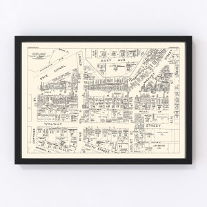 May include: A black and white map of a city with street names and building numbers. The map is framed in a black frame.