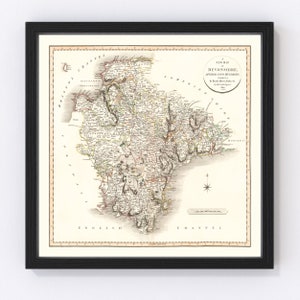 May include: An antique map of Devonshire, England, divided into hundreds. The map is printed on paper and has a cream background with brown, green, and red lines and text. The map is framed in a black frame.