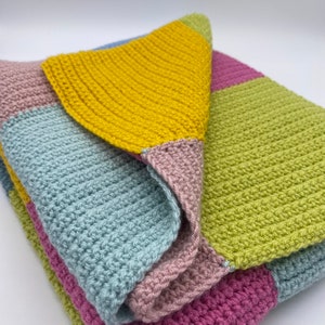 May include: A crocheted blanket with squares in shades of pink, blue, green, and yellow.