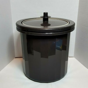May include: A brown plastic ice bucket with a lid. The bucket has a textured, ribbed design and a black knob on the lid.