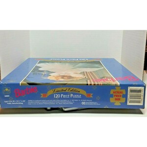 May include: A blue box with a Barbie 120 piece puzzle. The puzzle features a Barbie doll in a white dress with a blue background. The box has the words "Limited Edition" and "120 Piece Puzzle" on it.