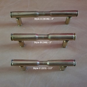 May include: Three different styles of brass bullet shell drawer pulls. The top pull is 4 inches long and labeled "Style A (30-06) - 4"". The middle pull is 3 inches long and labeled "Style B (308) - 3"". The bottom pull is 2.5 inches long and labeled "Style C (223) - 2.5"".