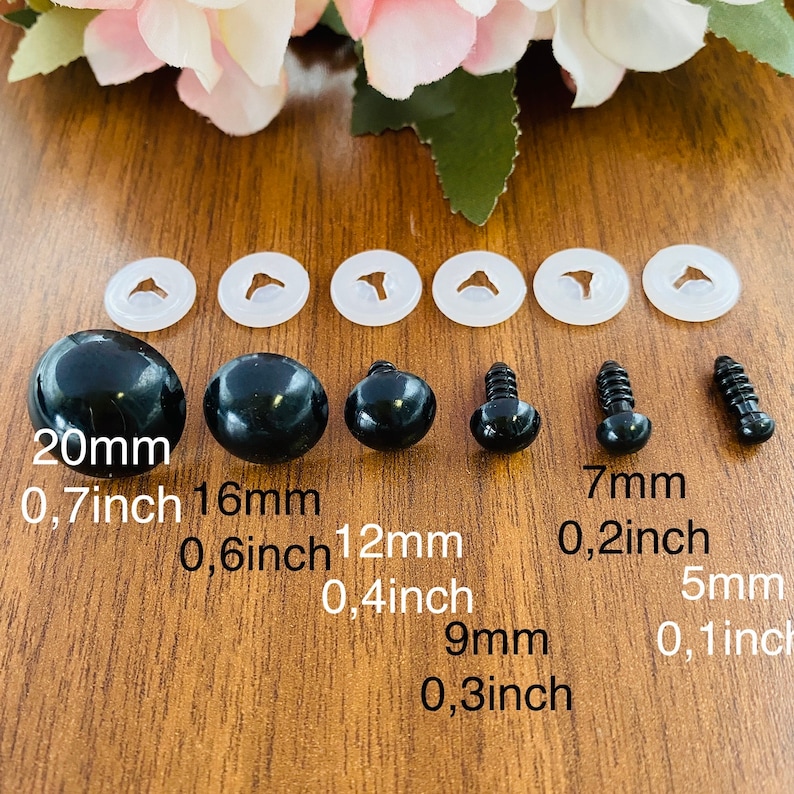 May include: A set of six black plastic safety eyes in graduated sizes from 5mm to 20mm, each paired with a clear plastic washer. The sizes are labeled as 20mm (0.7 inch), 16mm (0.6 inch), 12mm (0.4 inch), 9mm (0.3 inch), 7mm (0.2 inch), and 5mm (0.1 inch).