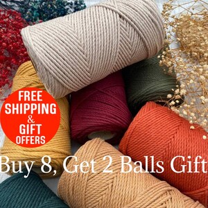 May include: A collection of colorful macrame yarn spools in shades of beige, mustard yellow, burgundy, olive green, and orange. The image includes text that reads "Buy 8, Get 2 Balls Gift".