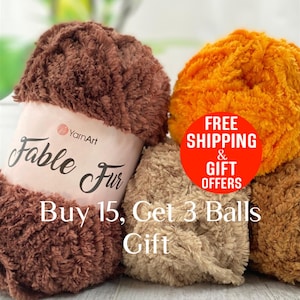 May include: Close-up of several balls of YarnArt Fable Fur yarn in various colors. The yarn is fluffy and textured, with a soft, fur-like appearance. The image includes text that says "Buy 15, Get 3 Balls Gift".