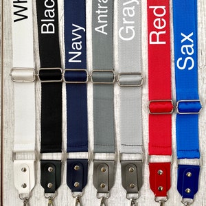 May include: Seven adjustable bag straps in white, black, navy, anthracite, gray, red, and sax blue. Each strap features a woven fabric band, a silver-toned metal slider, and a matching faux leather end piece with two silver rivets and a swivel hook.