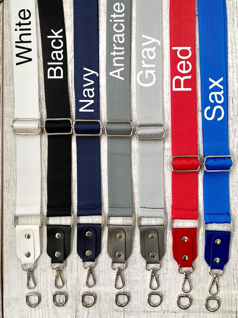 May include: Seven adjustable bag straps in white, black, navy, anthracite, gray, red, and sax blue. Each strap features a woven fabric band, a silver-toned metal slider, and a matching faux leather end piece with two silver rivets and a swivel hook.