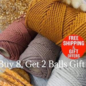 May include: Close-up of several spools of macrame cord in various colors, including dusty rose, mustard yellow, and gray. The cords are tightly wound, showcasing their texture. The image suggests a craft or DIY project.
