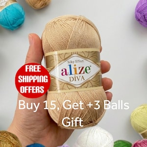 May include: A beige ball of Alize Diva yarn with a silky effect label, surrounded by multiple other colourful yarn balls. The central label features the brand name Alize Diva in a stylised font, with decorative gold patterns on the paper band.