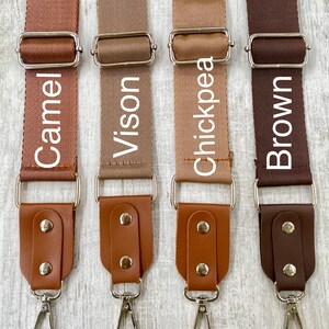 May include: Four adjustable bag straps in shades of Camel, Vison, Chickpea, and Brown. Each strap features a woven fabric section, a silver metal slider, and a leather-like end piece secured with two silver rivets and a silver swivel lobster clasp.