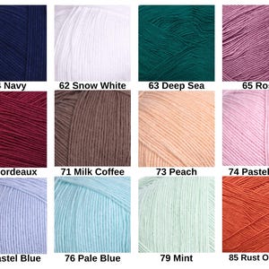 Puede incluir: Una cuadr&iacute;cula de doce ovillos de lana de varios colores etiquetados con n&uacute;meros y nombres: 54 Navy, 62 Snow White, 63 Deep Sea, 65 Rose, 66 Bordeaux, 71 Milk Coffee, 73 Peach, 74 Pastel Pink, 75 Pastel Blue, 76 Pale Blue, 79 Mint, 85 Rust Orange.