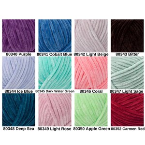 May include: A collection of twelve skeins of soft, plush yarn in various colors. Colors include purple, cobalt blue, light beige, bitter, ice blue, dark water green, coral, light sage, deep sea, light rose, apple green, and carmen red. Each skein is labeled with a number.