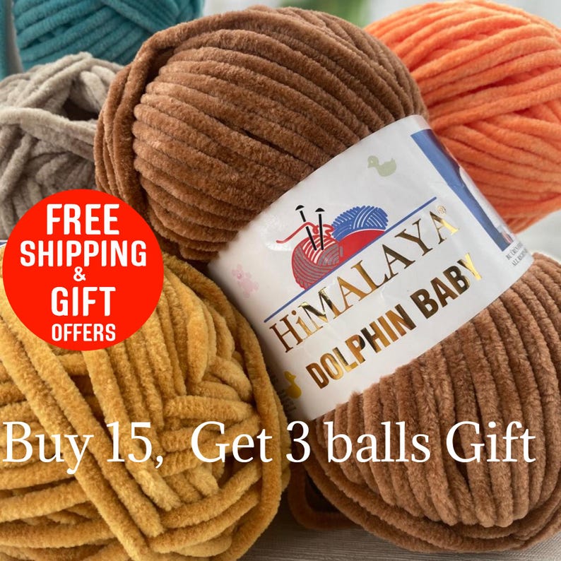 May include: Close-up of several balls of Himalaya Dolphin Baby yarn in various colors, including brown, orange, teal, and yellow. The brown yarn ball is in focus, with a label that reads "Himalaya Dolphin Baby." The yarn has a soft, velvety texture.