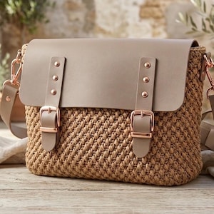Peut inclure: Un sac cartable structuré avec un corps en crochet beige texturé et un rabat lisse de couleur taupe. Le sac comprend deux sangles verticales avec des boucles et des rivets couleur or rose, ainsi qu'une bandoulière taupe assortie fixée par des fermoirs en métal couleur or rose.