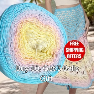 May include: A large ball of gradient yarn featuring a color transition from bright blue to soft yellow and pale pink. Beside the yarn is a crocheted skirt with a matching blue, yellow, and pink ombre pattern, showcasing an intricate openwork design.