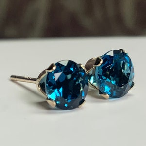 May include: A pair of gold stud earrings with round, deep blue gemstones.