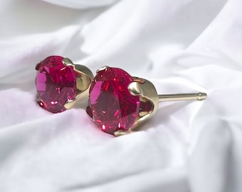 May include: A pair of gold stud earrings with bright red round gemstones.