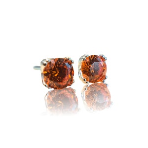May include: A pair of silver stud earrings with orange round gemstones.