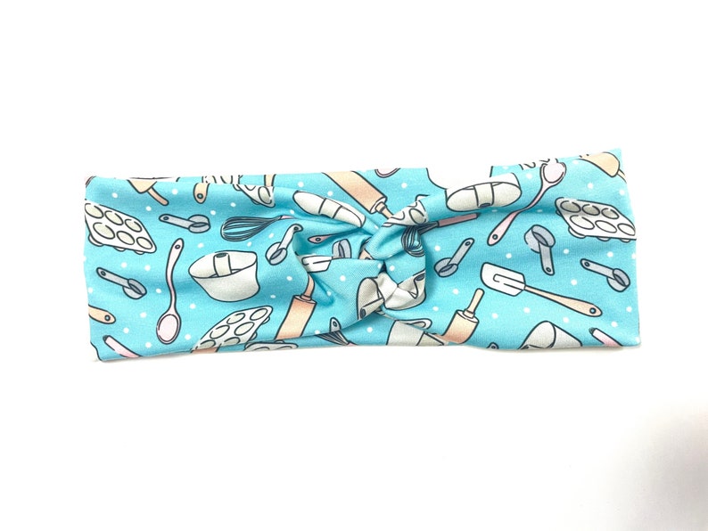 May include: A light blue headband with a white background and a pattern of various baking tools, including rolling pins, whisks, spatulas, and measuring cups.