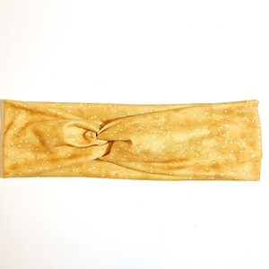 Puede incluir: Una diadema amarilla anudada con lunares blancos.