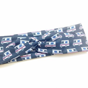 Könnte beinhalten: Ein schwarzes Stirnband mit einem weißen Postwagenmuster. Das Stirnband ist aus weichem, dehnbarem Stoff und perfekt, um die Haare aus dem Gesicht zu halten.