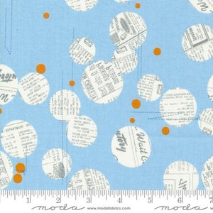 May include: Blue fabric with a white and orange polka dot pattern. The white dots are filled with a newspaper print. The fabric has a ruler with the word "moda" printed on it.