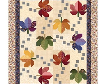 May include: A rectangular quilt featuring a cream-colored background with a pattern of multi-colored fabric leaves in shades of red, orange, yellow, purple, and green. Small grey squares are scattered throughout, framed by a dark blue and floral border.
