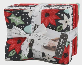 May include: A stack of Christmas-themed fabric squares, wrapped with a white ribbon printed with measurements. The fabric features red poinsettias, white flowers, and green leaves on a black background. A small tag with a woman's image is attached.