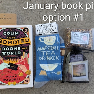 May include: A gift set including a book, blue socks with "Awesome Tea Drinker" text, tea, and a small bag with amethyst and starlight items. The book is titled "Colin Gets Promoted and Dooms the World." A reading list is also included.