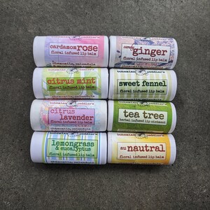May include: Eight different flavoured lip balms in white tubes with colourful labels. The labels feature floral designs and the names of the flavours: Cardamom Rose, Candy Ginger, Citrus Mint, Sweet Fennel, Citrus Lavender, Tea Tree, Lemongrass & Eucalyptus, and Au Nautral.