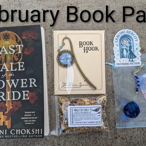 May include: A February Book Pack including a book titled "The Last Tale of the Flower Bride", a bookmark, a tea bag, a blue crystal, and a sticker with the text "Leaving Reality Entering Fiction".
