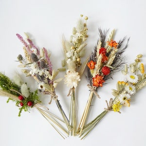 May include: Six small bouquets of dried flowers, each tied with twine. The bouquets feature a variety of colors and textures, including white, cream, pink, orange, red, and green.