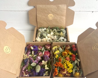 May include: Three small cardboard boxes filled with dried flowers. The boxes are open and the flowers are visible. The flowers are in shades of white, purple, and yellow. Each box has a sticker that says "handmade with love".