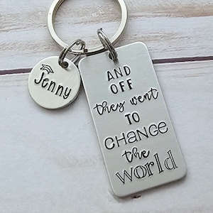 May include: Silver keychain with a graduation cap charm and a rectangular tag that reads "And off they went to change the world".