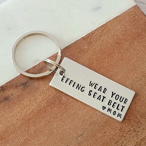 May include: Silver keychain with a rectangular tag that reads "Wear your effing seat belt ♥ Mom".