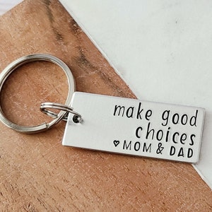 May include: Silver keychain with a rectangular tag that reads "make good choices ♥ MOM & DAD".