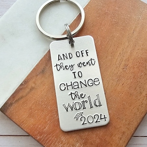 May include: Silver keychain with a graduation cap and the text "AND OFF they went TO CHANGE the world 2024".