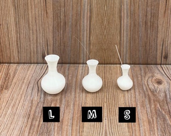 May include: Three white ceramic vases in different sizes, labeled L, M, and S. The vases are on a wooden surface. The text "THE NORA" is at the top of the image.