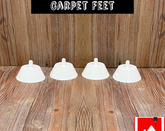 May include: Four white plastic furniture feet with a raised center point. The feet are arranged in a row on a wooden surface. The text "MEOWANT SC02 CARPET FEET" is visible at the top of the image.