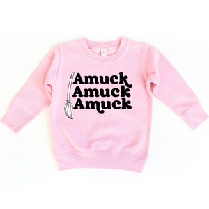 May include: Pink long-sleeved sweatshirt with a black graphic of a broom and the text "Amuuck Amuuck Amuuck".