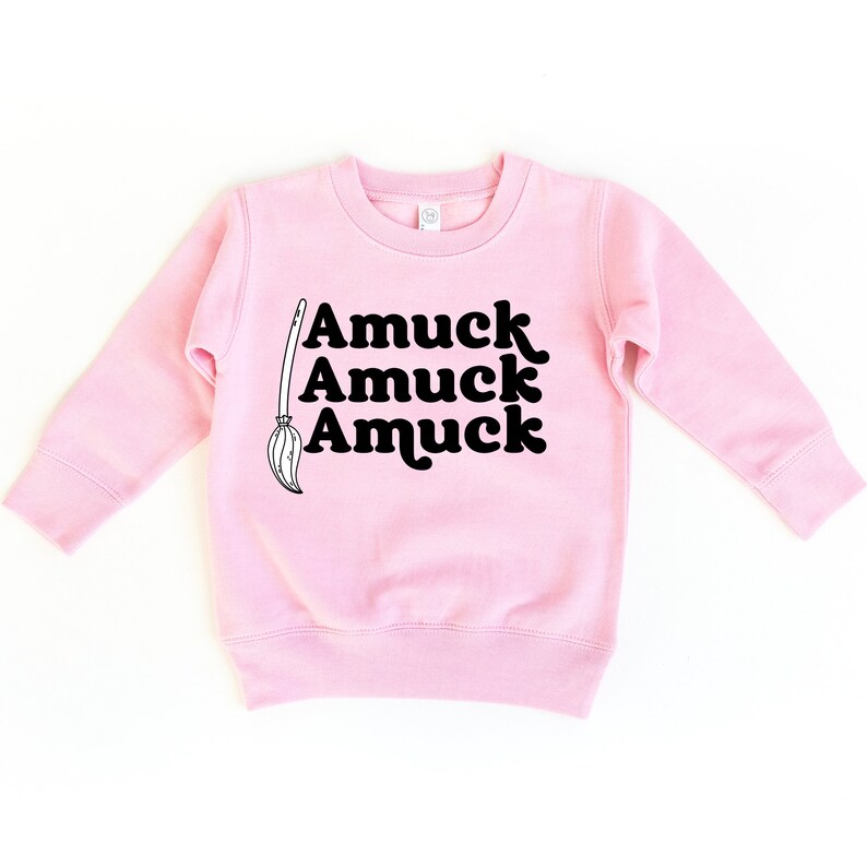 May include: Pink long-sleeved sweatshirt with a black graphic of a broom and the text "Amuuck Amuuck Amuuck".