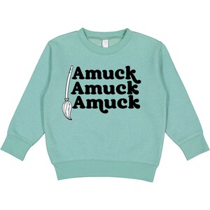 May include: A light blue sweatshirt with a black graphic of a broom and the text "Amuuck Amuuck Amuuck".