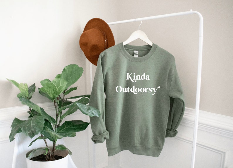 May include: Sage green sweatshirt with the text "Kinda Outdoorsy" in white lettering.