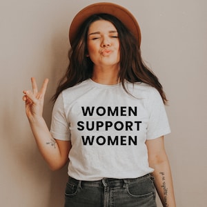 May include: A white t-shirt with the text "WOMEN SUPPORT WOMEN" printed in black.