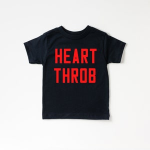May include: A black t-shirt with the words "HEART THROB" printed in red.